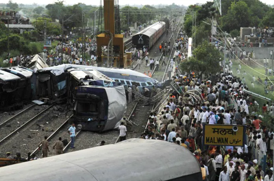 Derailed Kalka Mail coaches near Malwan railway station in Fatehpur, Uttar Pradesh, as rescue workers and crowds gather at the accident site.